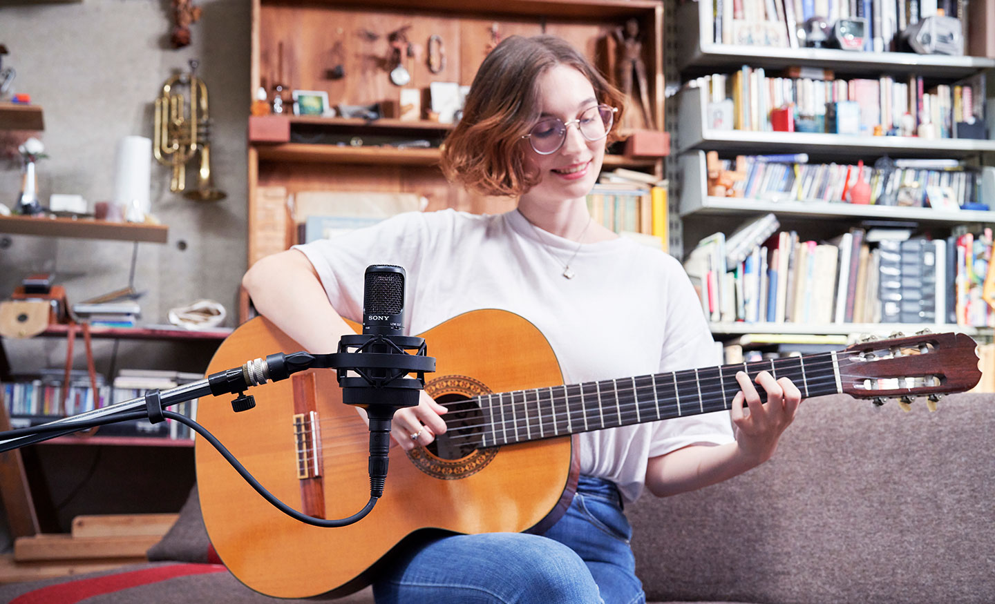  Image of a woman playing an acoustic guitar and recording with a Sony C-80 Uni-directional condenser microphone