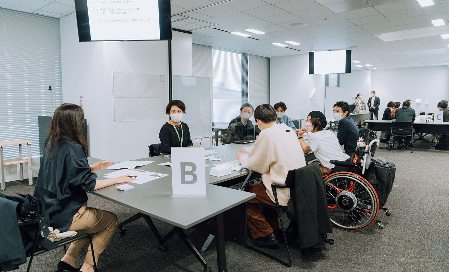 Des employés et une personne en fauteuil roulant discutent, assis autour d'une table