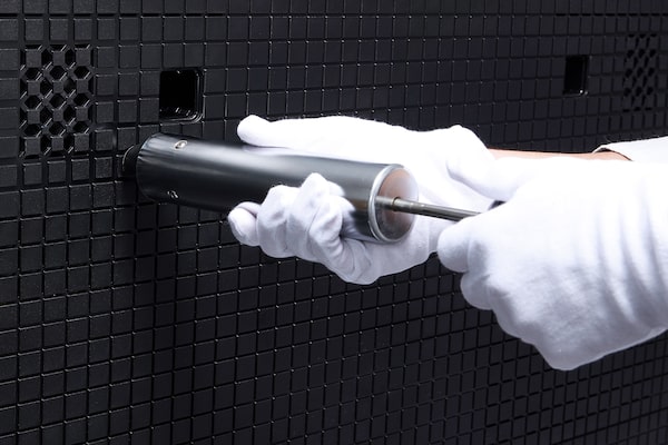 Close-up image of plastic panel, with a person wearing gloves holding a tool.