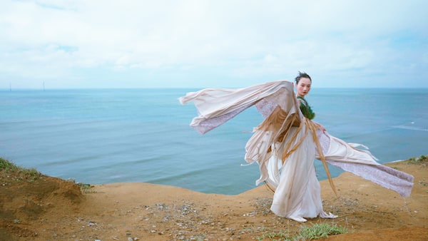 Example image showing woman in period costume with coastline in background