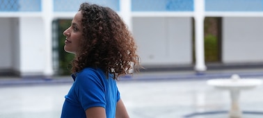 Example image of a woman walking along a bright courtyard corridor, looking towards the courtyard centre