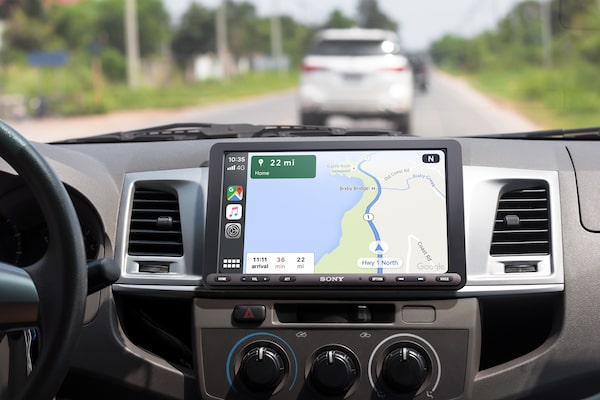 Image of the 8.95" (22.7cm) Digital Media Receiver with WebLink Cast inside a car with a driver using Apple CarPlay navigation.