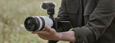 Usage image of a man shooting hand-held video with telephoto lens attached